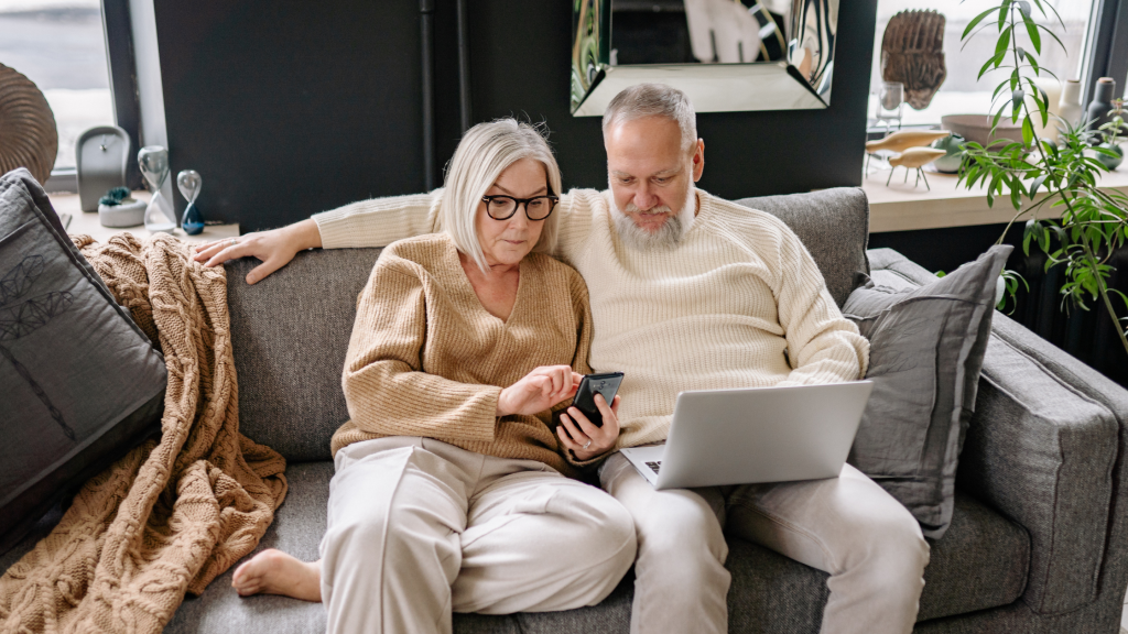 Senior couple with a laptop and mobile device analyzing the market.